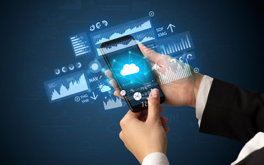 Female hand using smartphone with financial tracking concept illustrated by graphs and symbols