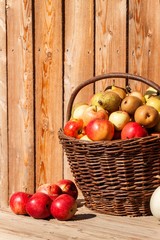 Fototapeta na wymiar Wicker basket with apples and pears. Autumn harvest of fruit. Fresh fruit in a basket.