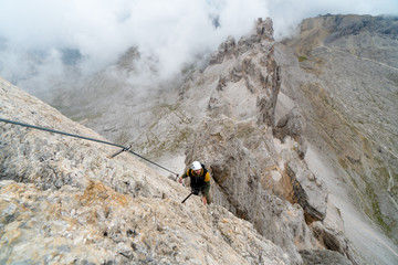 young male mountain climber on a steep and exposed Via Ferrata in Alta Badia in the South Tyrol in...