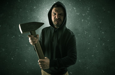 Masked armed villain in empty dark room with gun ax chainsaw mallet wrench
