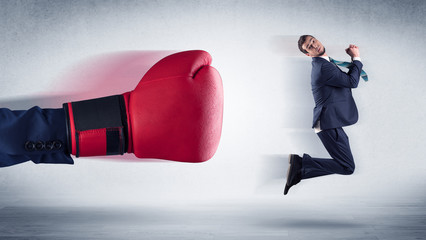 Big red boxing gloves hitting little businessman concept
