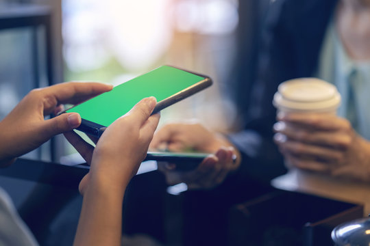 Modern business woman order hot coffee from barista and using smartphone to pay by scanning QR Code in coffee shop. Modernization society cashless, no cash. Easy payment for new social network