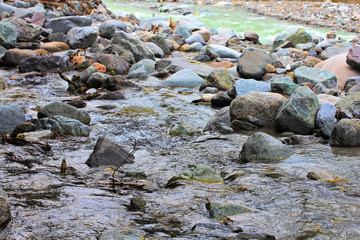 large granite stones lie next to the blue mountain stream
