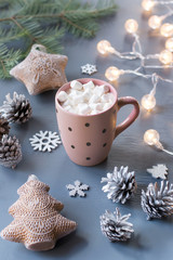 Winter background with hot drink with marshmallows, Christmas lights, fir tree and decorations.