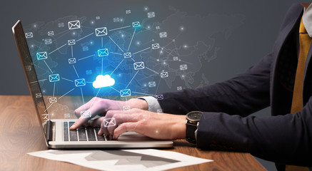 Businessman hand sending a bunch of messages on laptop with cloud computing concept
