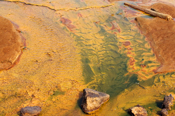 yellow water in a shallow river poisoned by copper production