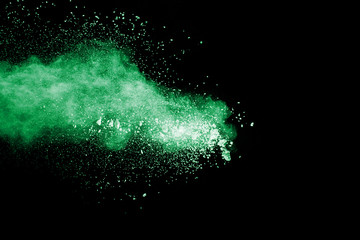 Green color powder explosion cloud  on black background.Green dust splash on dark background.
