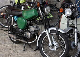 Fototapeta premium Dunkelgrünes Moped auf grauem Kopfsteinpflaster
