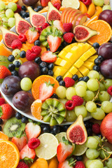 Fototapeta na wymiar Variety of healthy raw fruits and berries background, strawberries raspberries oranges plums apples kiwis grapes blueberries, mango, vertical, selective focus