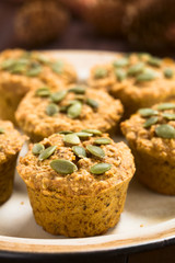 Frische hausgemachte gebackene Kürbis, Walnuss und Haferflocken Muffins mit Kürbiskernen bestreut (Selektiver Fokus, Fokus auf die vorderen Kürbiskernen auf dem ersten Muffin)