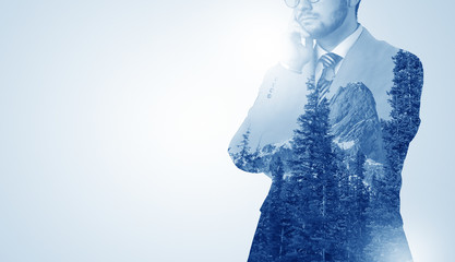 Young businessman standing and meditate with trees on the background 