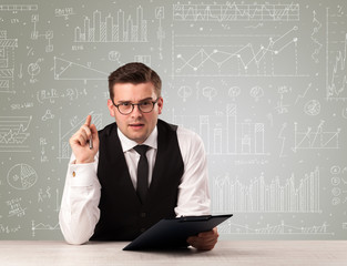 Young handsome businessman sitting at a desk with white graphs and calculations behind him 
