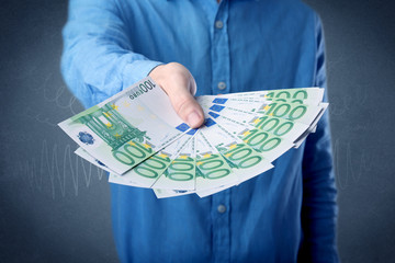 Young businessman holding large amount of bills with grungy background