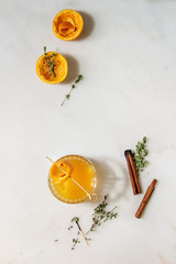 Glass of Scotch Whiskey orange juice alcohol cocktail with swirled orange peel on skewer tyme herbs...