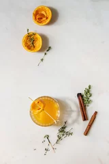  Glass of Scotch Whiskey orange juice alcohol cocktail with swirled orange peel on skewer tyme herbs and cinnamon sticks standing on white marble background. Flat lay, space © Natasha Breen