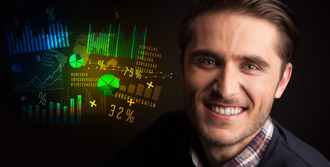 Portrait of a young businessman with colorful charts and graphs next to him on a dark background