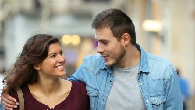 Front view of a happy couple talking and walking towards camera