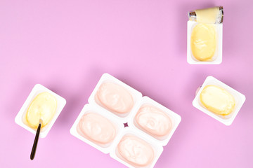 Plastic cup with tasty yogurt on lilac background. Top view. Space for text or design.