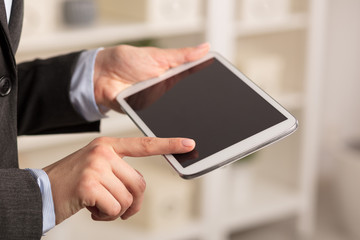 Business woman below chest using tablet in a homey environment

