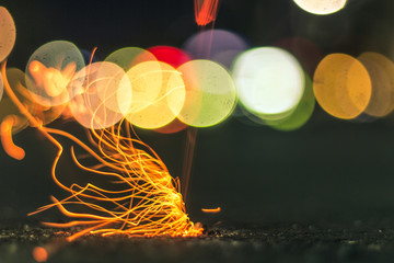 A long exposure of a cigarette being flicked, with colorful lights in the background