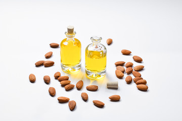 Bottles of almond oil and almonds  on white background, copyspace.