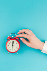 Woman hand holding the red vintage alarm clock