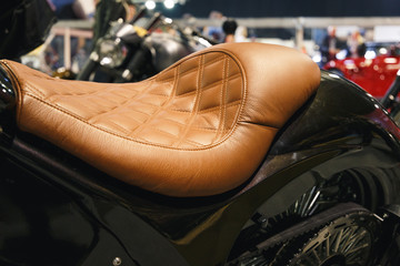 Leather motorcycle seat. Motorcycle with vintage, leather seat. Close-up seat and wheel of bike....