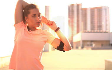 Young girl warming up outdoors, stretching triceps and neck muscles before workout.