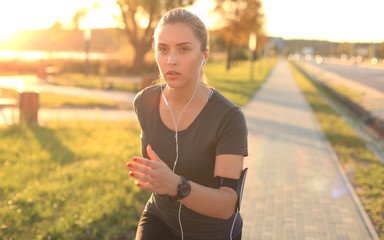 Young attractive sporty fitness woman running while exercising outdoors at sunset or sunrise.
