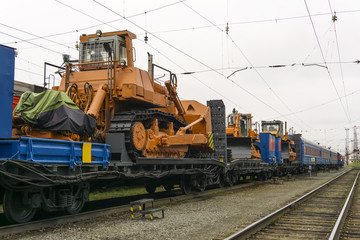 heavy orange bulldozers stands on the flatcar of the train for accident recovery work