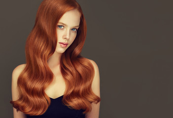 Red head girl with long  and   shiny curly hair .  Beautiful  model woman  with wavy  hairstyle....