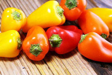 Fresh red, yellow and orange bell pepper on wooden background. raw vegetable.