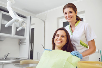 A girl with a beautiful smile with a dentist indoors.