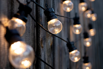Warm LED light bulb and blurred lights on old wooden background in the garden, copyspace, outdoor...