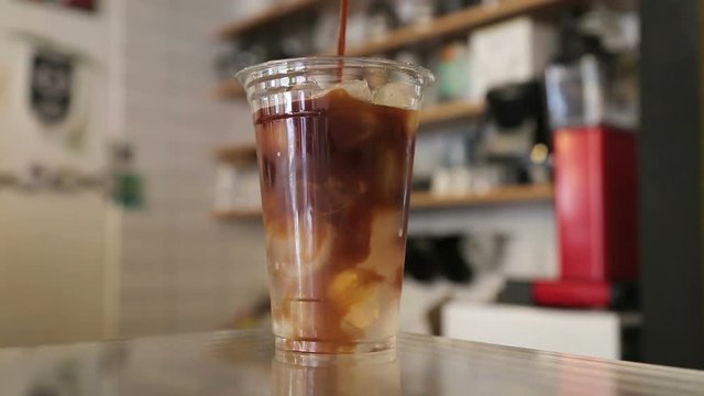 Ice Caff&egrave; Americano in coffeehouse. Barista pouring fresh coffee with milk into a glass of ice cubes.