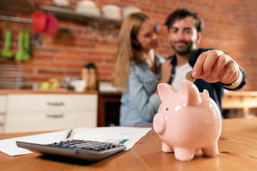 Happy couple inserting coin in piggybank