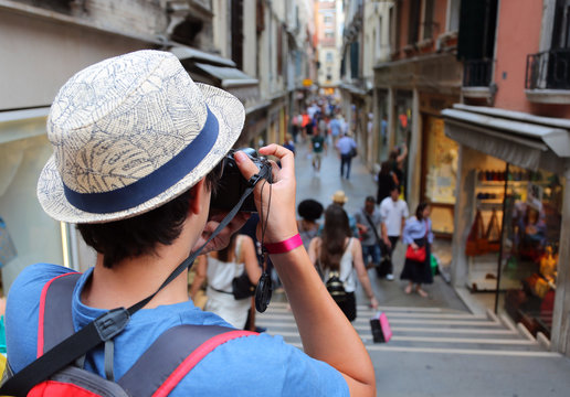 boy with digital camera takes many pictures of a narrow street c