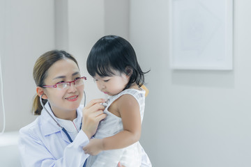 Obraz na płótnie Canvas Asian doctor using a stethoscope to check his breathing and heart of a lovely girl, check the health of children,Thailand people