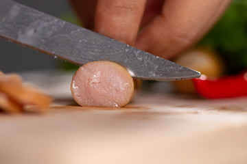 Cook is cutting sausage to prepare food