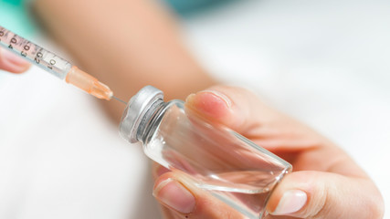 Closeup image of female doctor filling syringe with medication from ampule