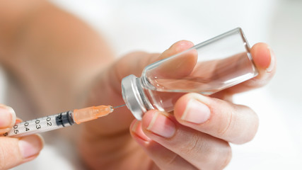 Closeup photo of female nurse filling small syringe with medication