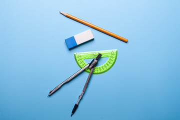 pencil, eraser, ruler and compass on blue background