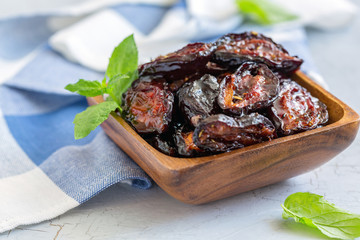 Spicy dried plums in a wooden bowl.