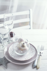 Silver and white Christmas Table Setting with christmas decorations above light window