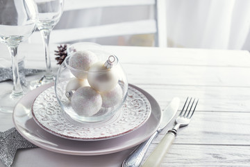 Silver and white Christmas Table Setting with christmas decorations above light window