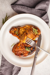 Baked steak pork with rosemary on a white plate, top view.