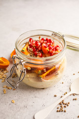 Overnight oatmeal with pomegranate, persimmon and hemp seeds, white background.