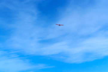 A small aircraft soars in the blue sky. Glider in the sky.