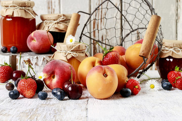 Summer fruits and three jars with jam