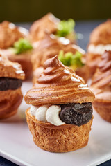 Savory profiteroles with different types of fillings. Salty cakes for snacks. Mini sandwiches, canapes with vegetables, meat, liver, sauce. An exquisite French snack for a buffet at the feast.